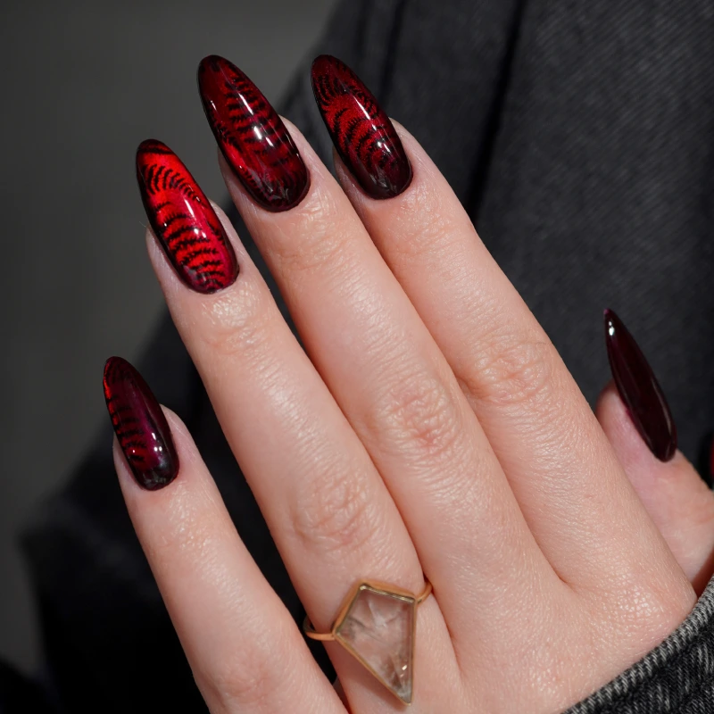 Red and black cat eye nails with fern print