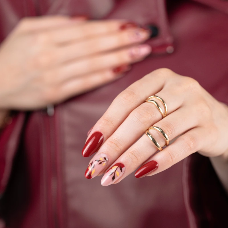 Red nails with botanical nail art on a milky base