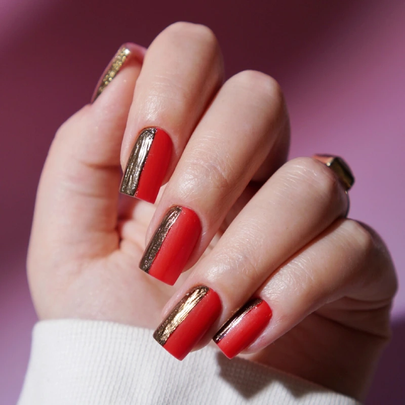 Red nails with gold chrome details along the sides