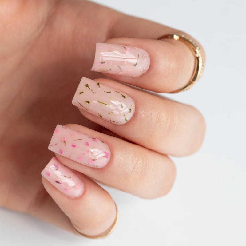 Milky pink spring nails with floral nail art and decorative flecks