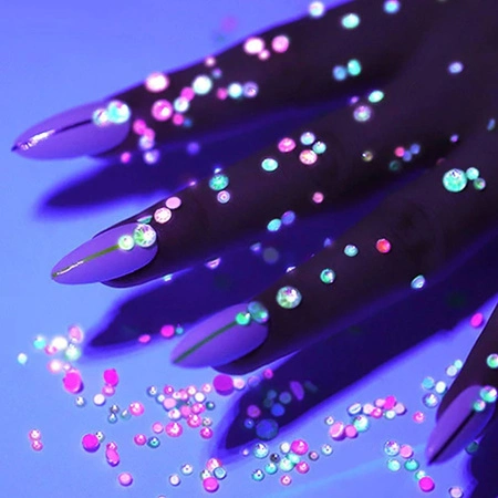 Manicure with glow-in-the-dark rhinestones photographed in the dark