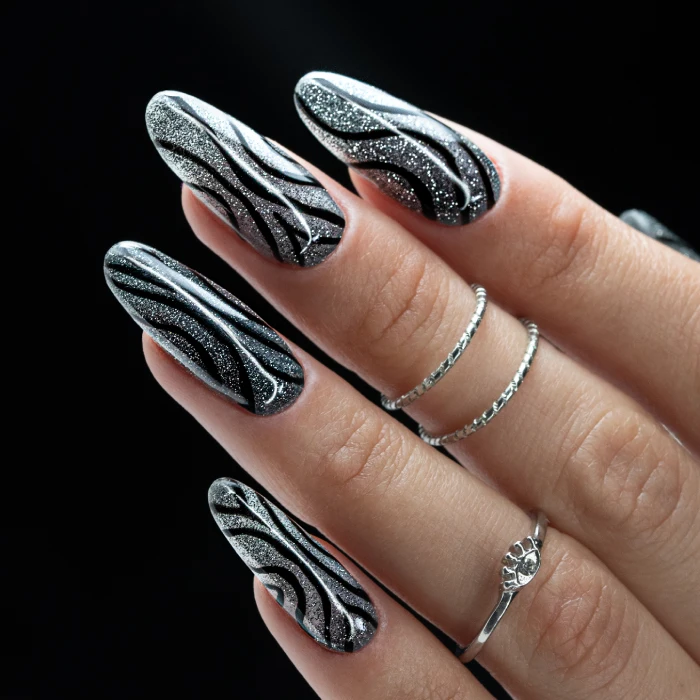 Long almond nails with silver swirls, black lines and a glitter finish