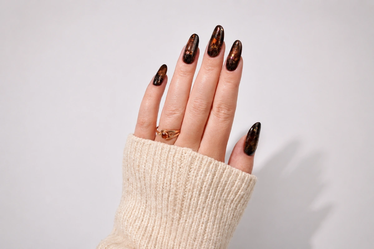 Amber-brown tortoiseshell nails on long almond-shaped nails