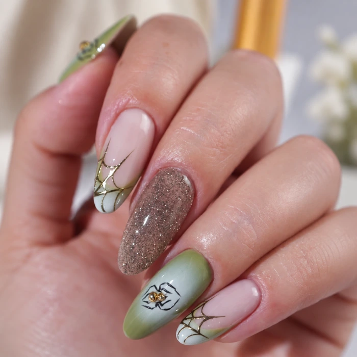 Long nude, gold and green nails with spider and spiderweb details